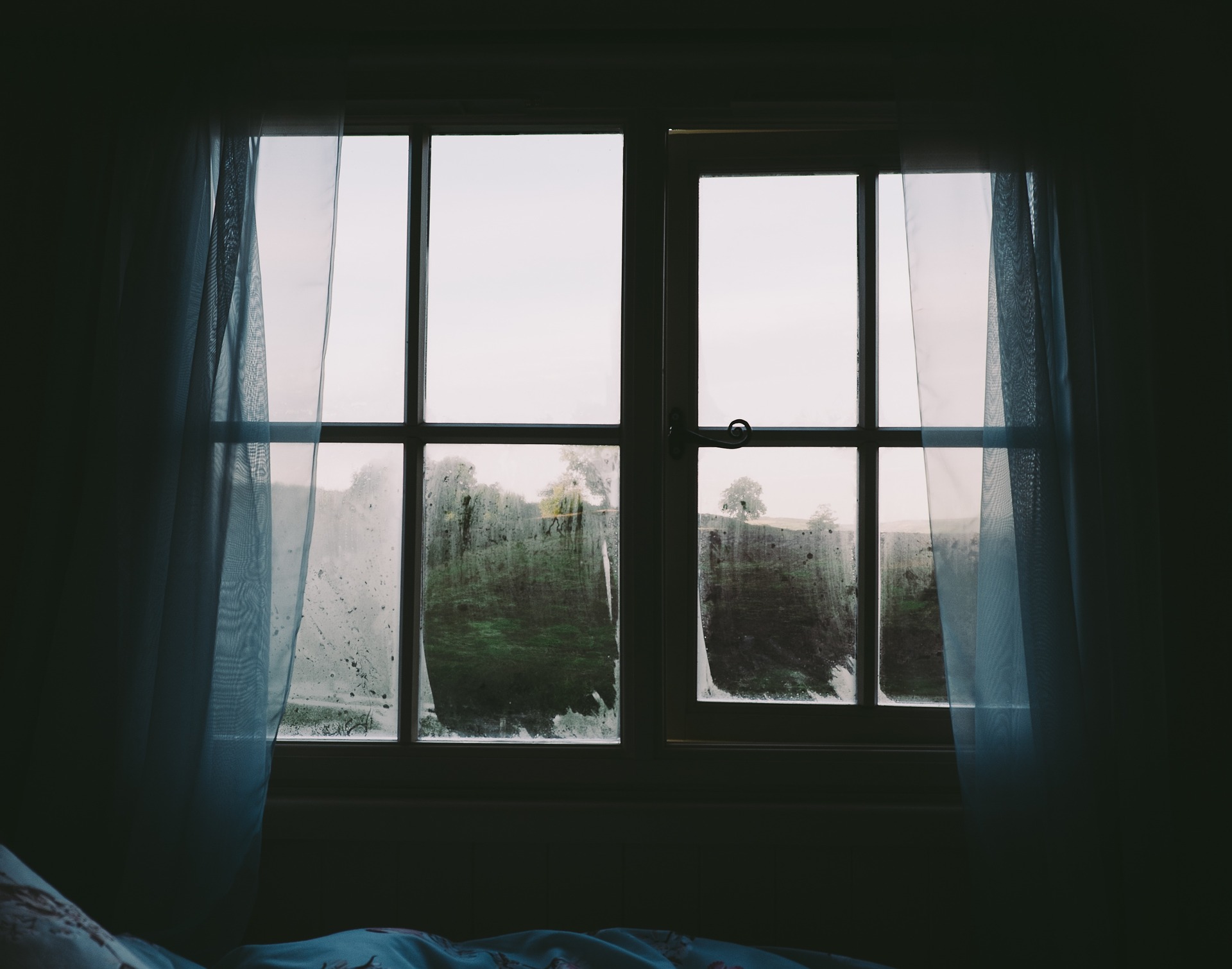 Ein dunkles Zimmer, der Blick geht durch Fenster nach draußen.