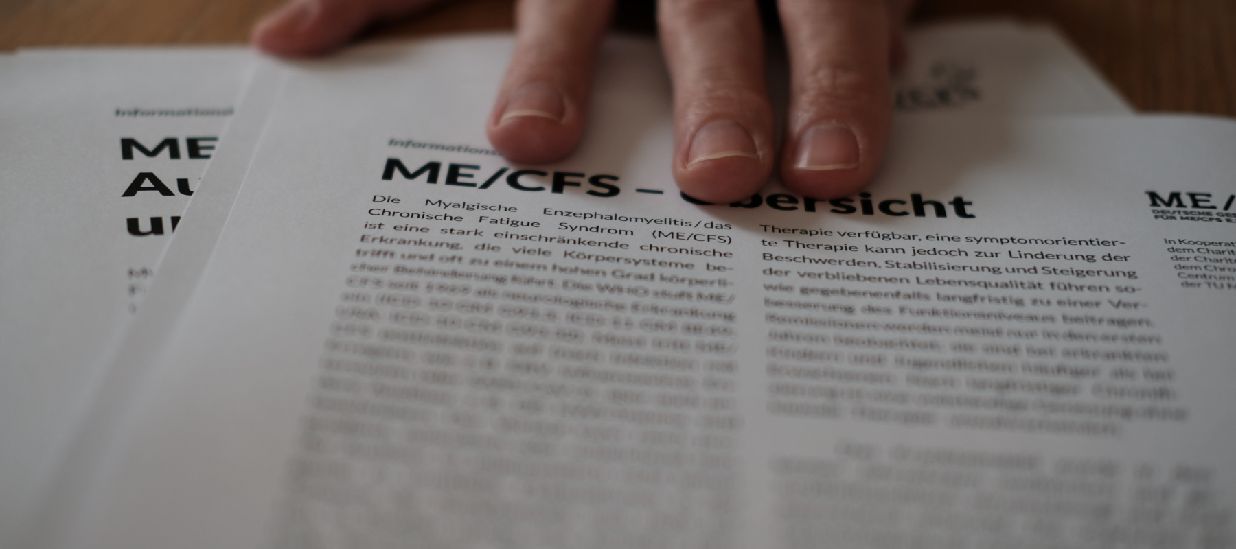 Eine Hand schiebt die Informationsblätter über den Tisch.